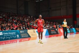 Male basketball player walking in front of big crowd