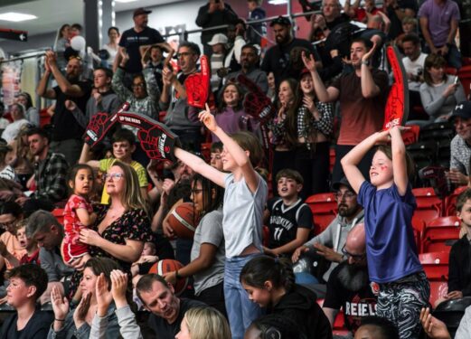 Crowd of fans cheering and some standing with their Rebels large foam hand