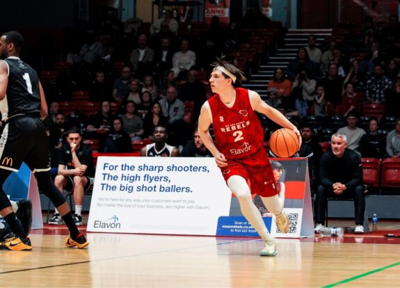 Men's Basketball player on court running with ball