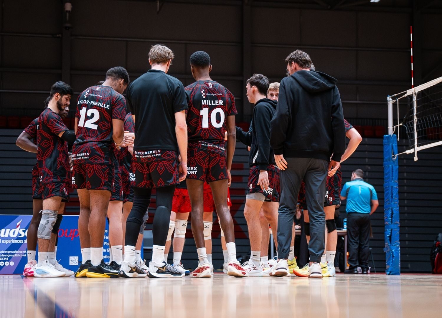 Men's Volleyball players huddled together talking on the court